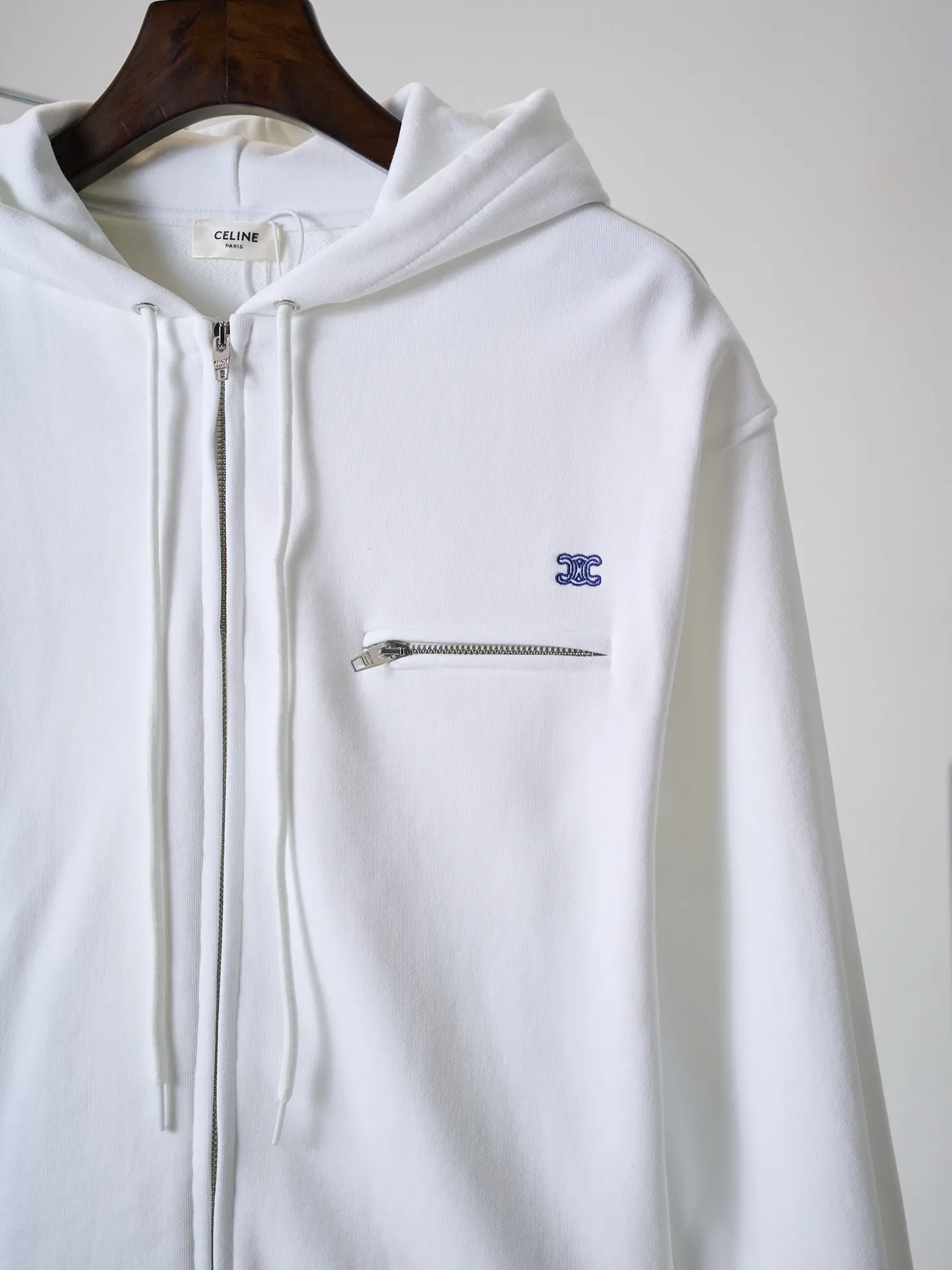 [Real auction] Celine/Celine logo embroidered zipper jacket (women's style) [In Stock] S M L custom-made light oxygen cotton-feel fleece knit, delicate and smooth, soft and skin-friendly. The body is laid out in clear white, with a soft cotton-like texture and rich layers. The elegant white tone brings a refreshing and clean daily atmosphere. The iconic Celine Arc de Triomphe embroidery is embellished on the chest, which is simple yet memorable. The simple hoodie silhouette sets a refreshing tone, and the two-way metal zipper design is full of texture. The short silhouette with loose, dropped shoulders gently modifies the lines of the shoulders and arms; the drawstring at the hem is adjustable to shape the silhouette as desired, and the short length optimizes body proportions. The simple silhouette carries a lazy atmosphere, and the relaxed outfit reveals the French girlish attitude. 1. Imported machine embroidery technology uses advanced computer control systems and precision mechanical components to precisely create the iconic TRIOMPHE logo embroidery, with smooth and delicate lines and a full sense of sophistication. 2. Fermentation washing treatment: The fabrics have been fermentation washing, which makes the hand feel and texture better, is not easy to deform, shrink, and fade, and maintains long-term beauty and loose fit.
